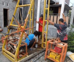 Tukang sumur bor melakukan pengeboran air tanah dengan mesin modern